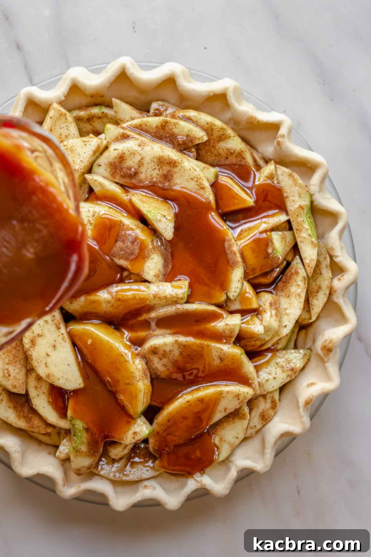 Salted caramel pouring over apples in a pie dish.