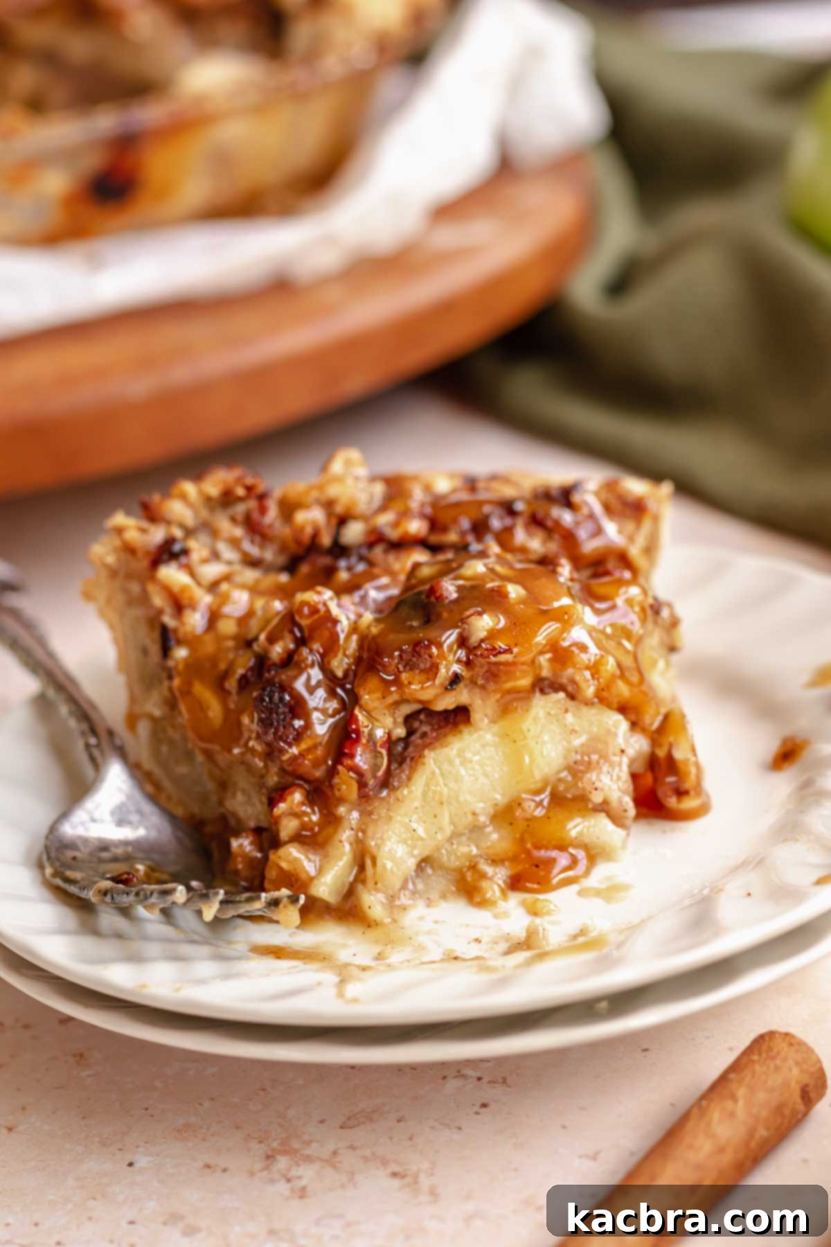 Slice of caramel apple pie on a plate with a bite removed.