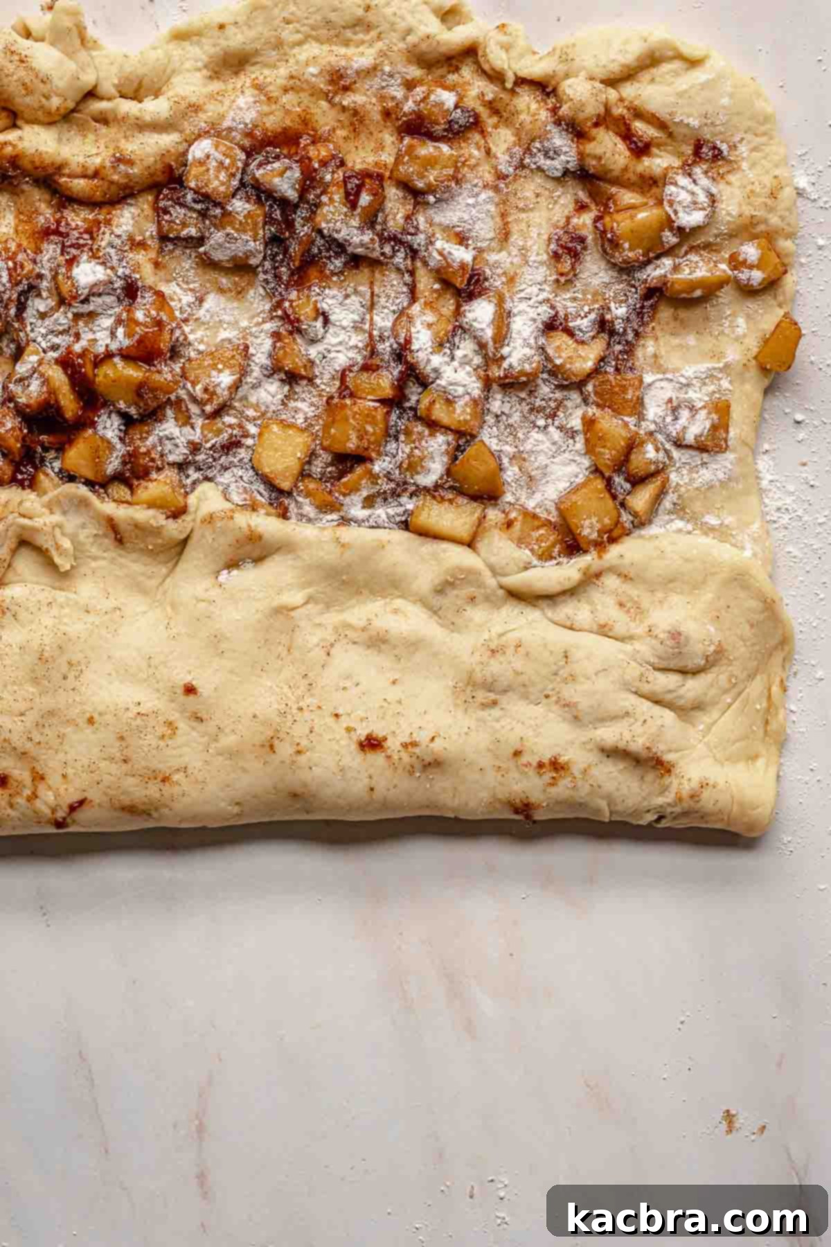 The dough expertly folded into thirds, encasing the apple filling completely within.