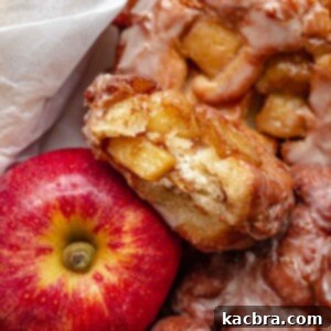 A basket of apple fritter donuts next to an apple. One it broken open.