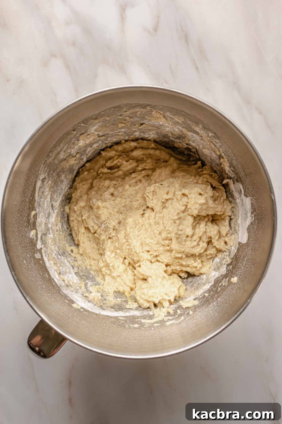 Shaggy brioche dough in a bowl of a stand mixer, indicating the initial mixing stage.