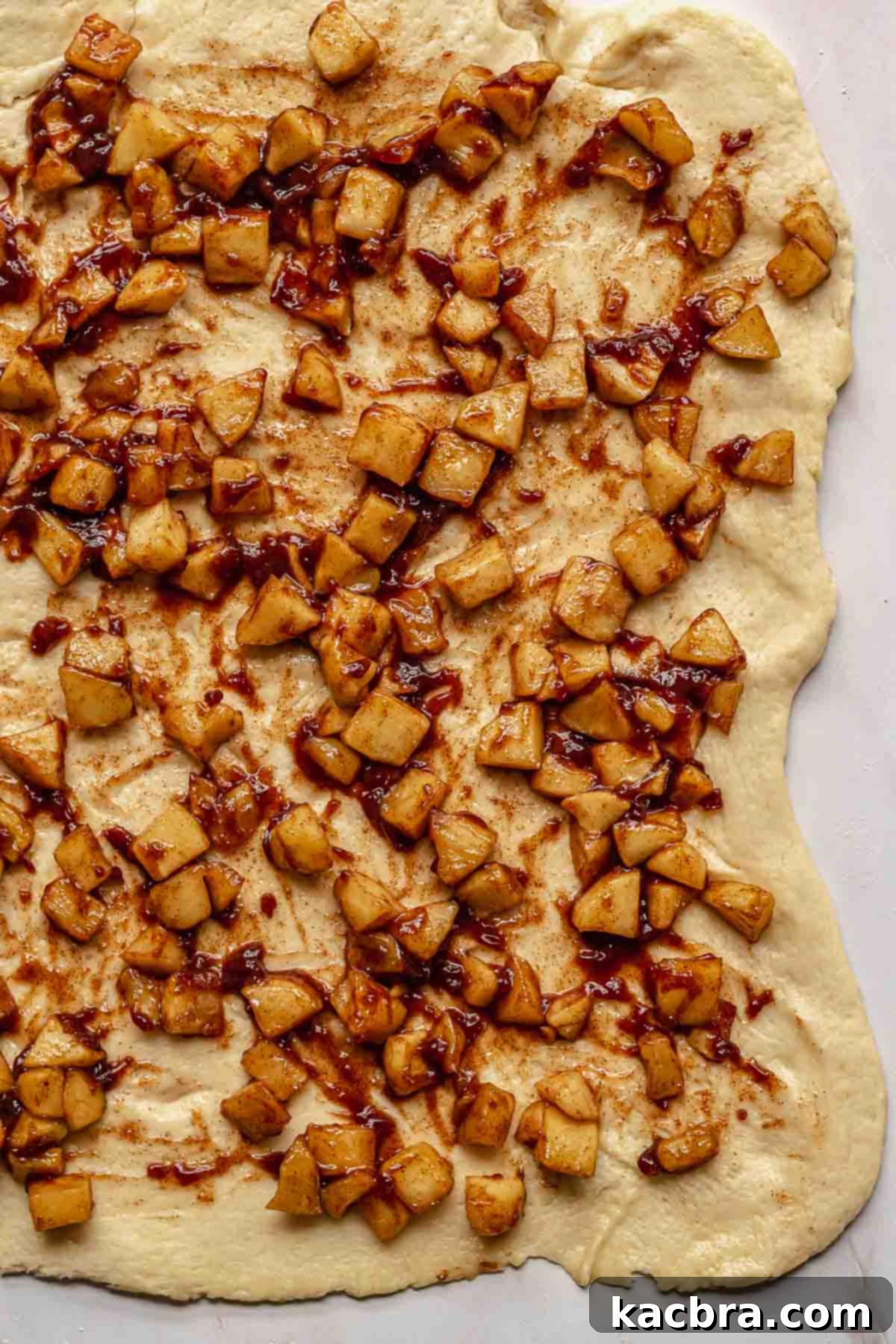Spiced, diced apples carefully spread evenly across the rolled-out brioche dough.