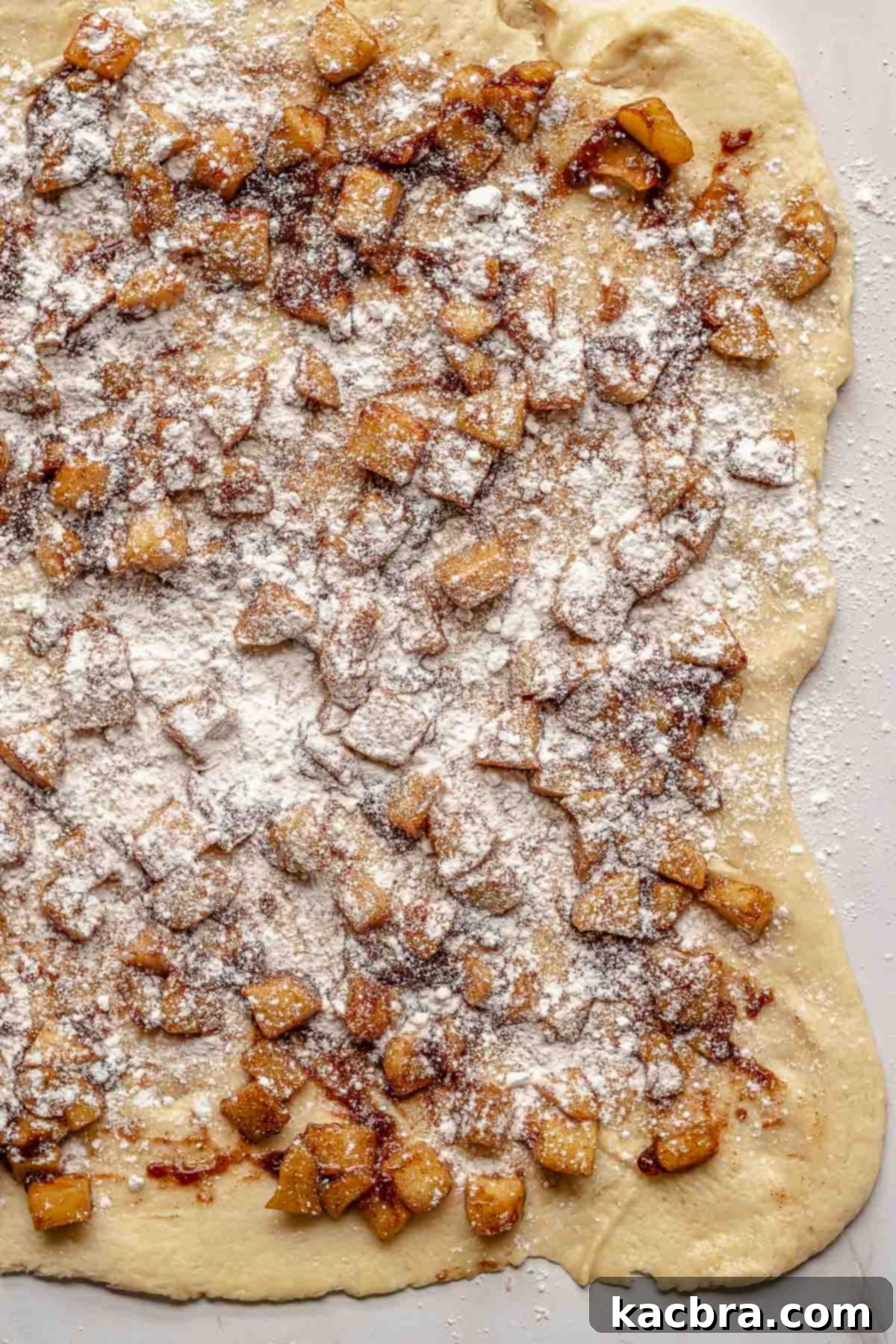 A light dusting of flour covering the spiced apples and dough, preparing it for folding.