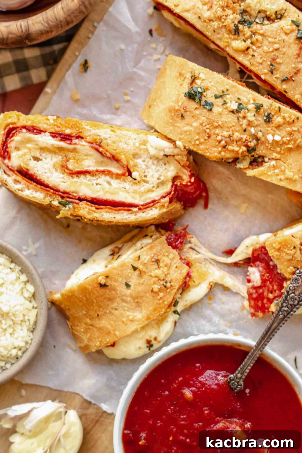 Pepperoni bread sliced on a board with one piece split with melty cheese.