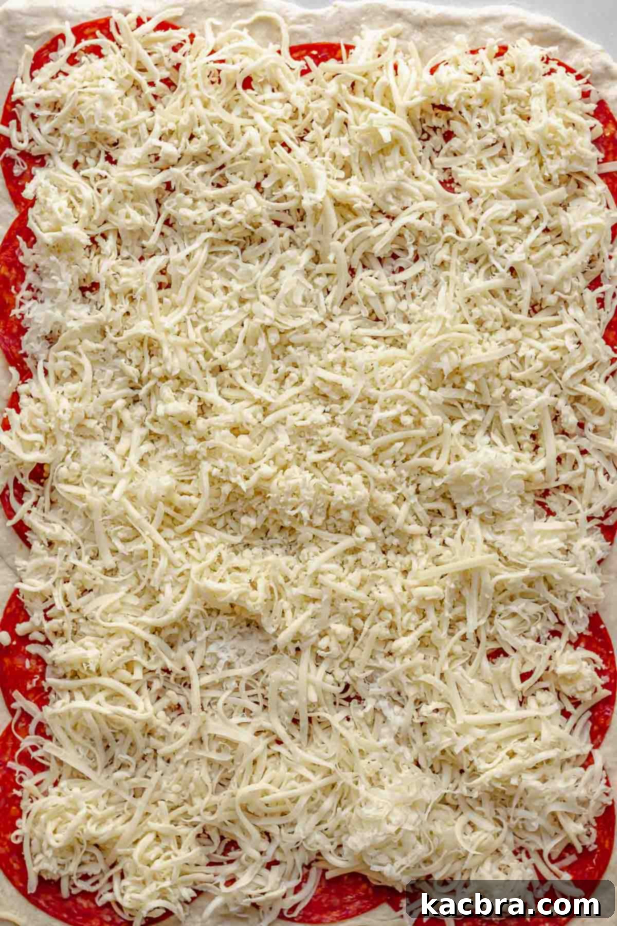 Parmesan and mozzarella cheese layered on top of pepperoni and dough.