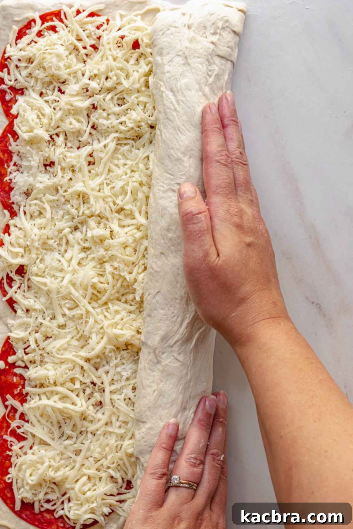 Hands roll up pepperoni bread like cinnamon rolls.