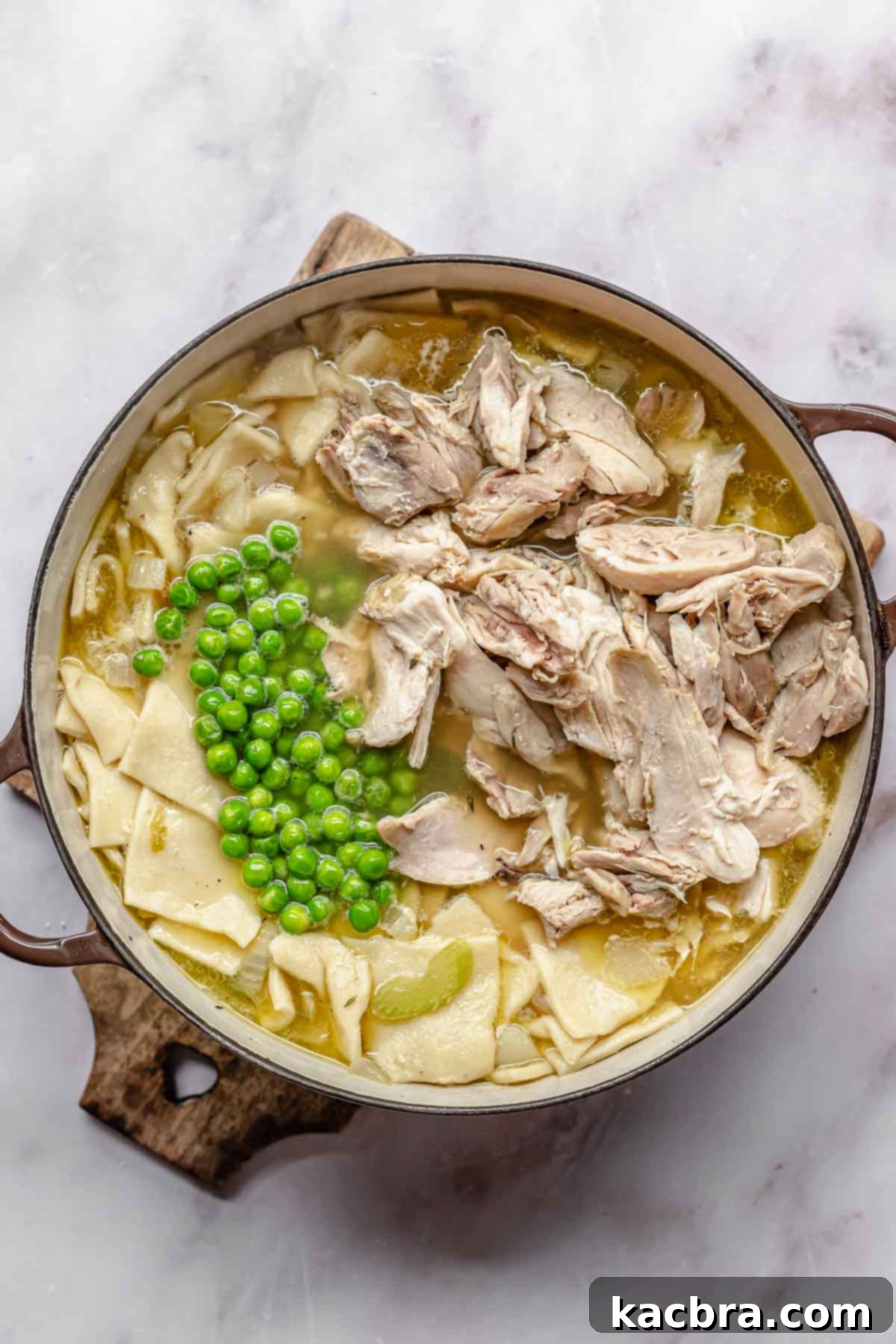 Peas and chicken on top of chicken soup and noodles.