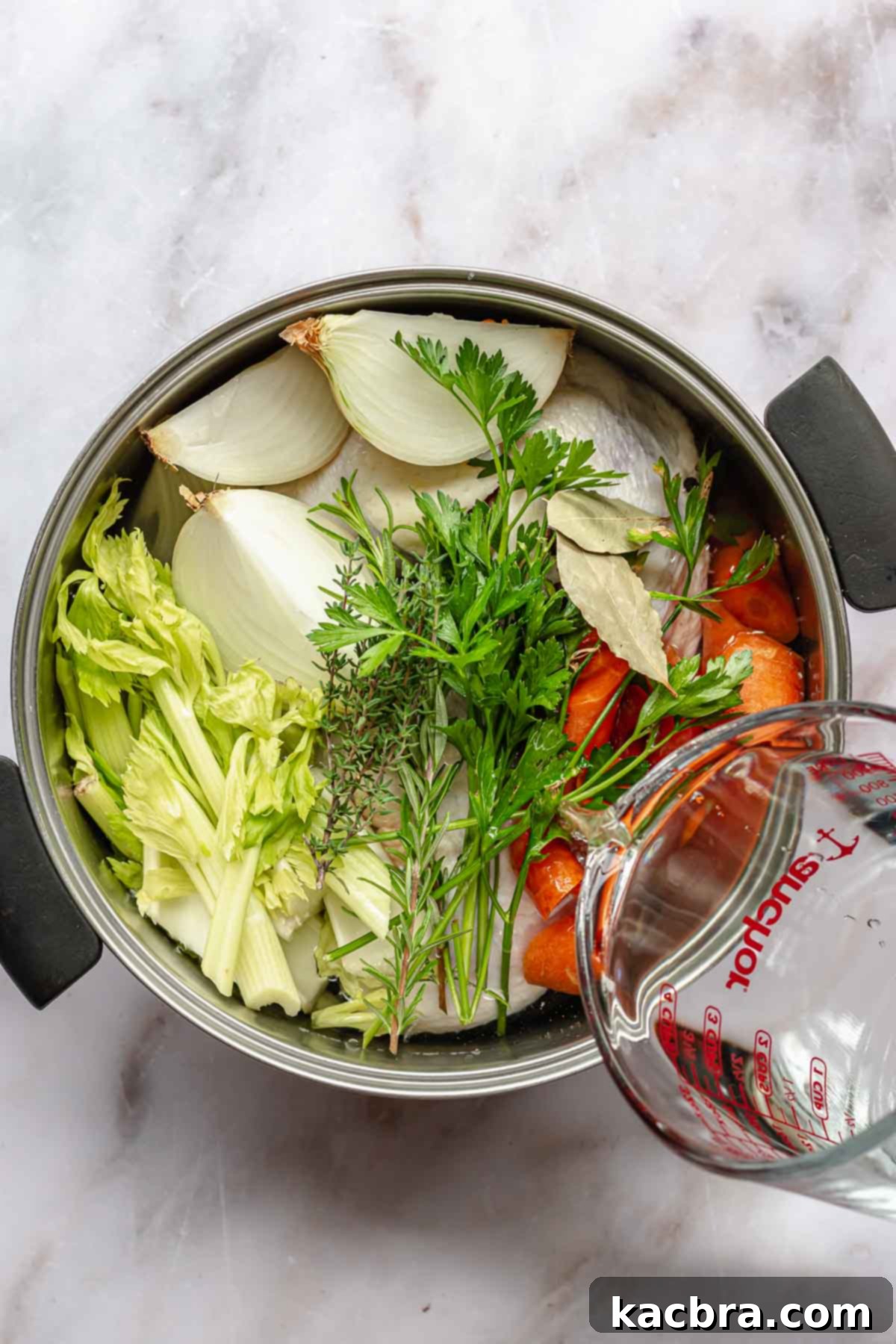 Water being poured into a pot of chicken stock before boiling.