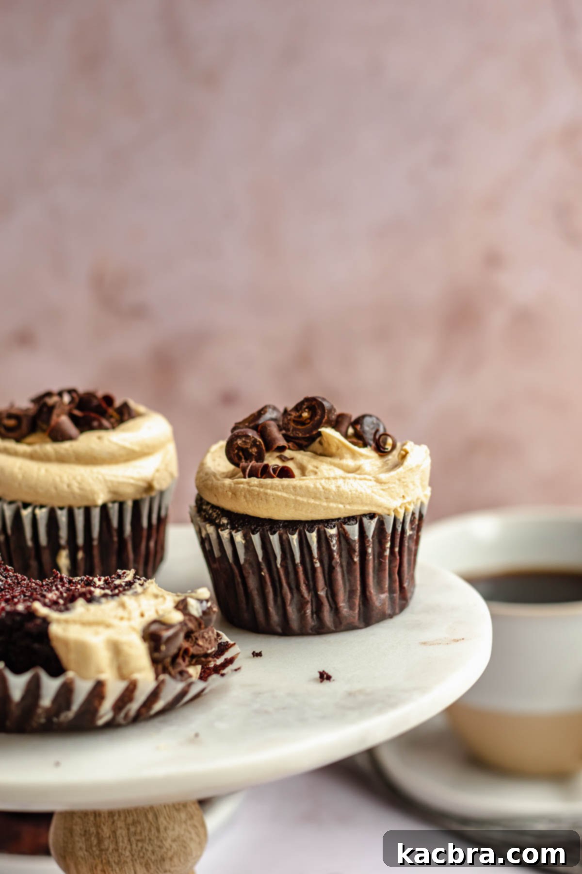 Chocolate coffee cupcakes with espresso frosting, garnished with coffee beans, artfully displayed on a small cake stand, ready to be enjoyed.