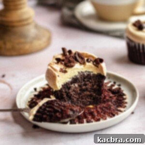 Mocha cupcake on a plate with a bite removed sitting on a spoon.