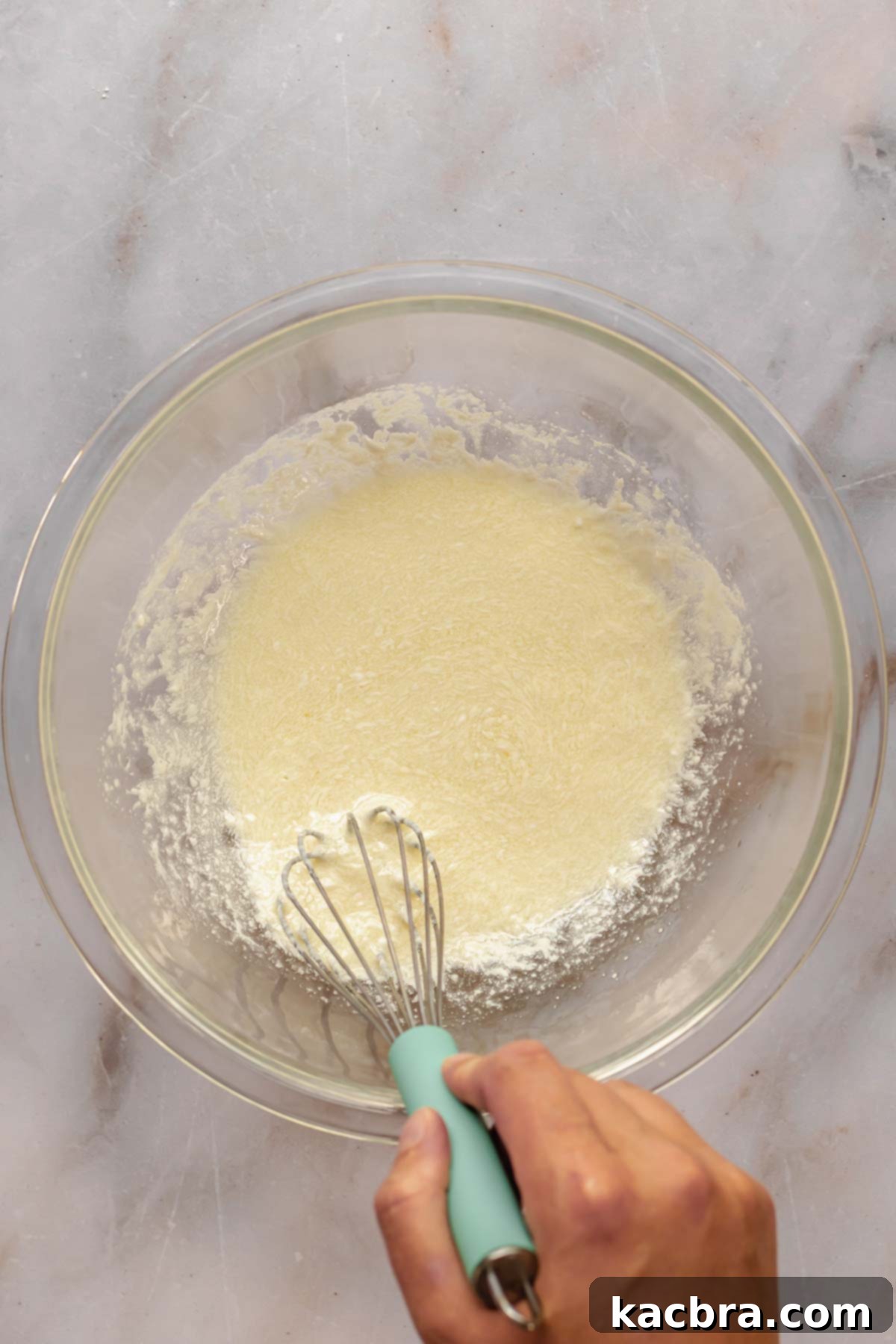 A whisk vigorously mixes together the wet ingredients for the chocolate mocha cupcakes in a separate bowl until well combined and smooth.