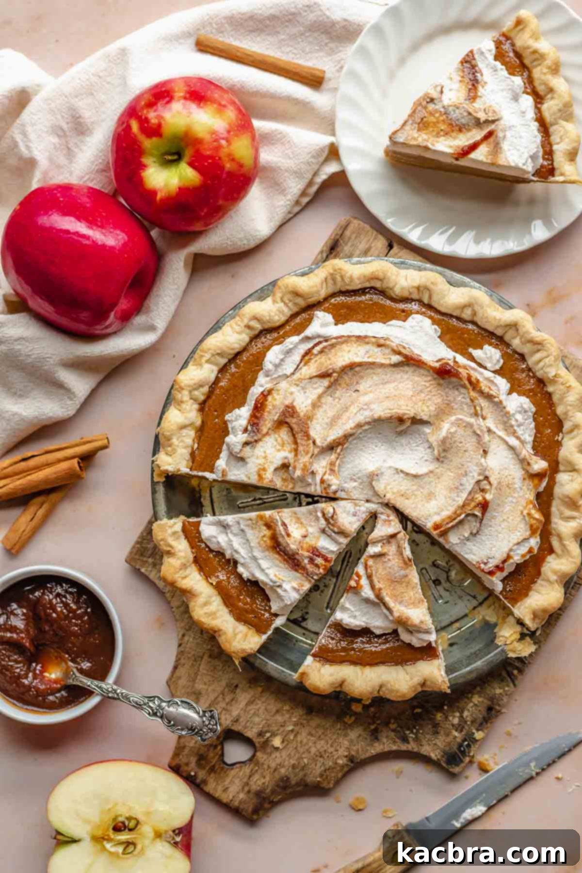 A beautifully presented apple butter pie with a slice carefully removed, revealing its creamy texture. On the side, fresh apples and a jar of rich apple butter are arranged, highlighting the pie's key ingredients and natural essence.