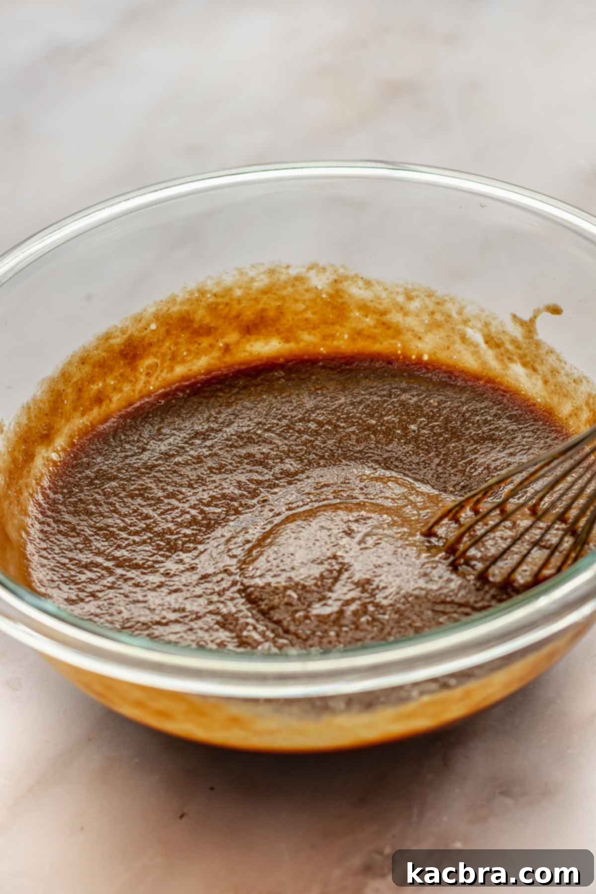 A whisk vigorously mixes creamy filling ingredients in a large bowl, creating a smooth and consistent batter for the apple butter pie.