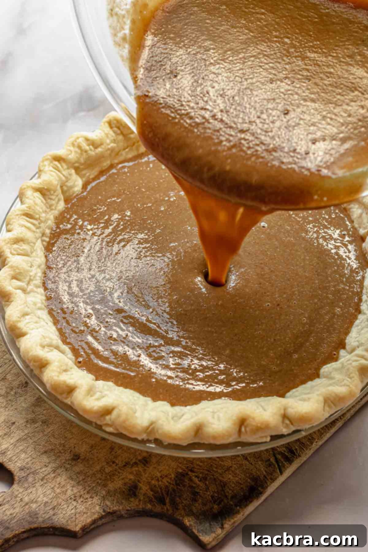 The rich, smooth apple butter pie filling is poured into a beautifully par-baked pie crust, preparing it for baking.