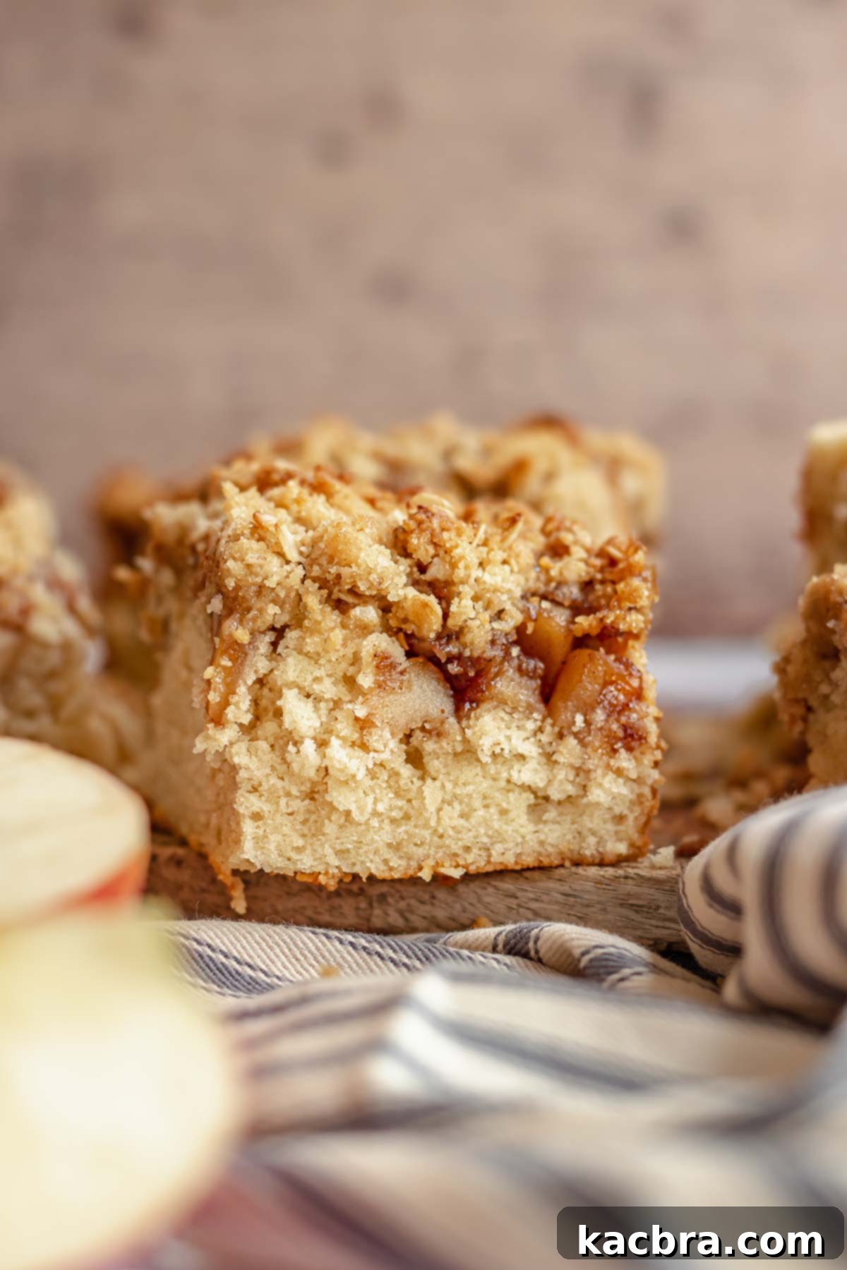 A perfectly baked slice of apple streusel coffee cake, revealing its moist cake layer, spiced apple filling, and generous crumb topping.