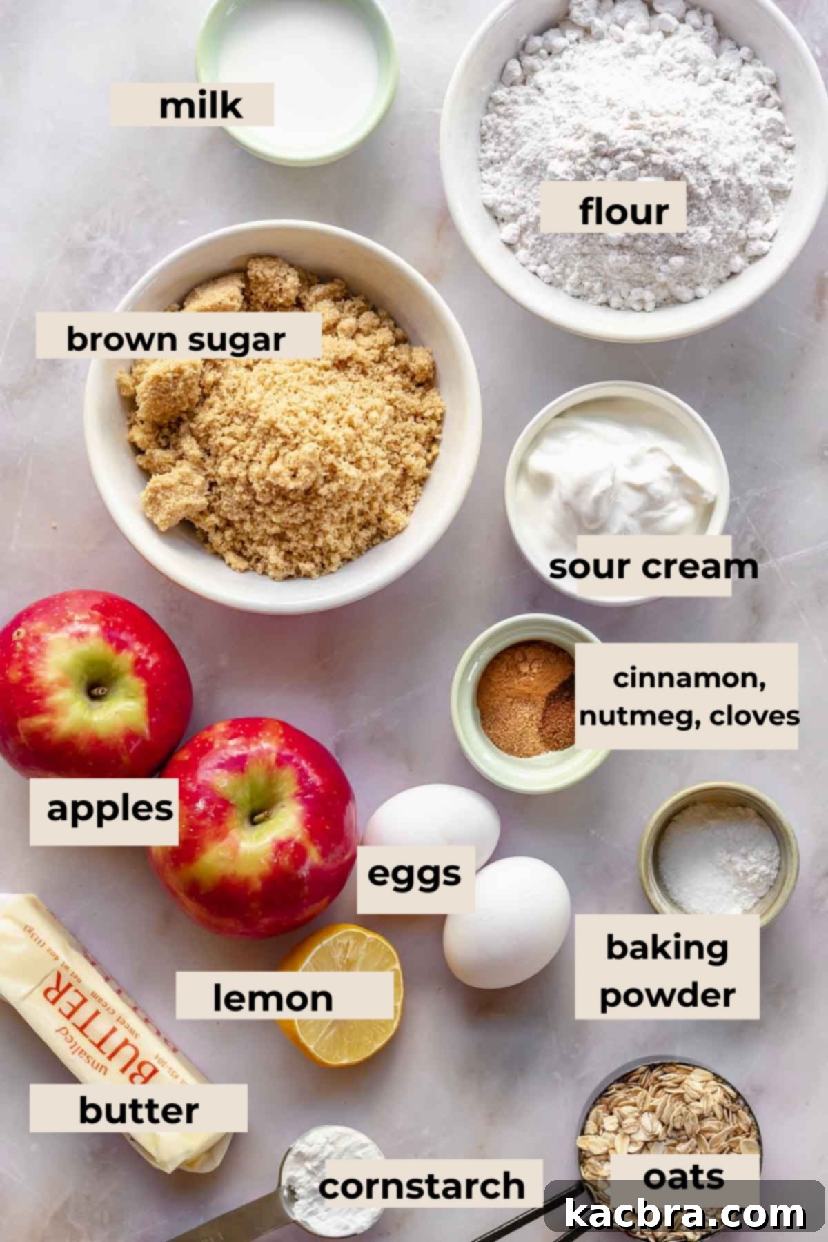 A collection of fresh ingredients laid out for baking apple streusel coffee cake, including apples, flour, butter, and spices.