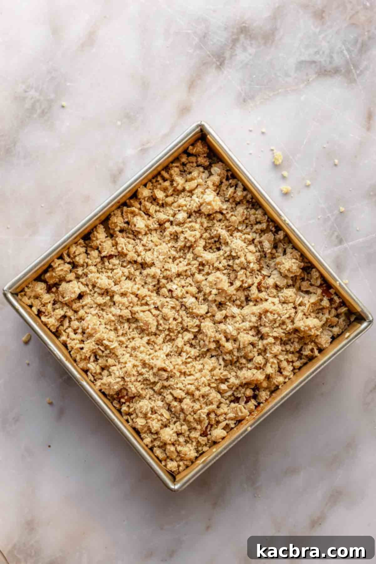 Crumb topping generously sprinkled over the apple layer on top of the coffee cake, ready for baking.