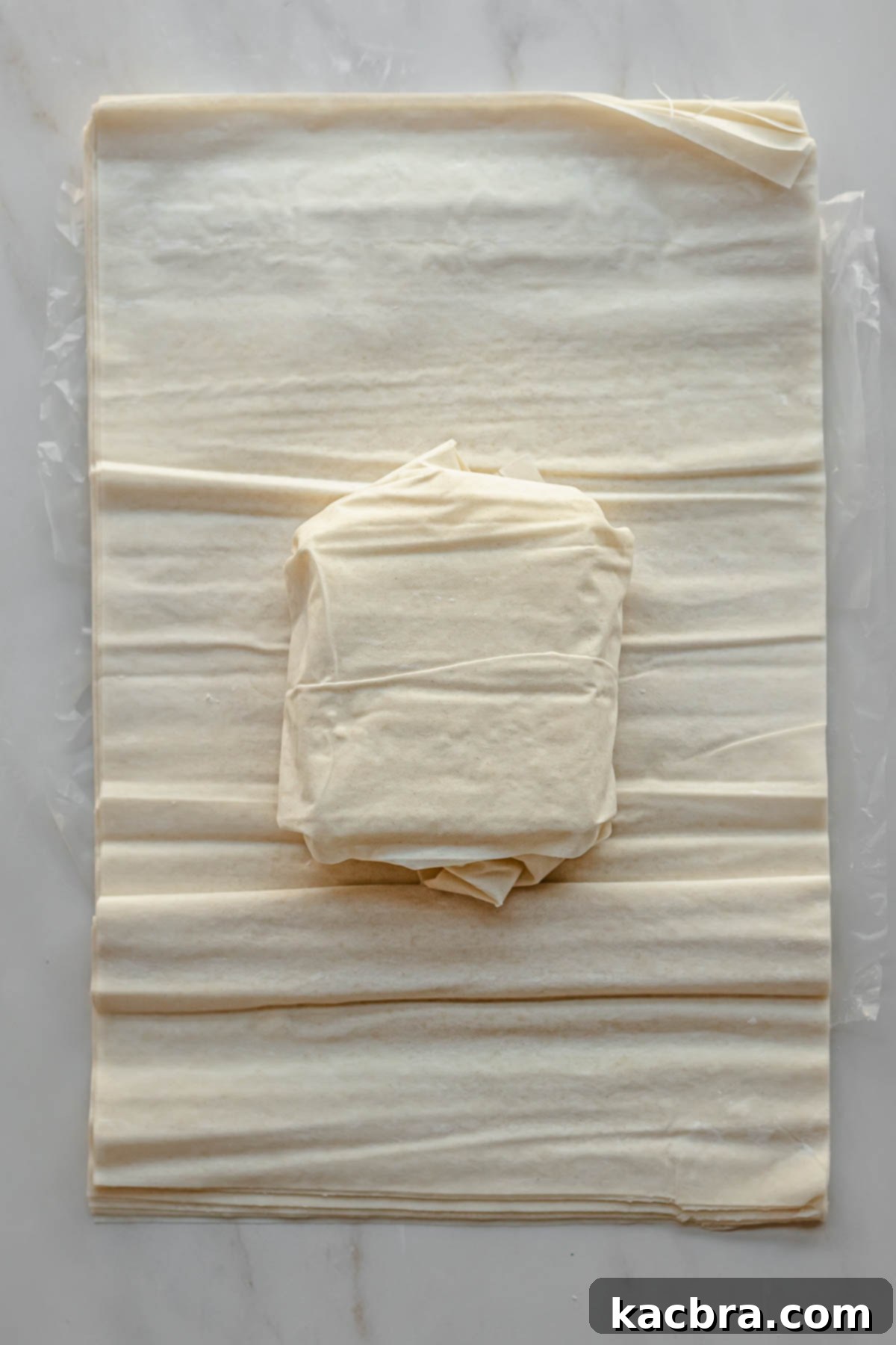 Feta wrapped in phyllo sitting on top of more phyllo sheets.