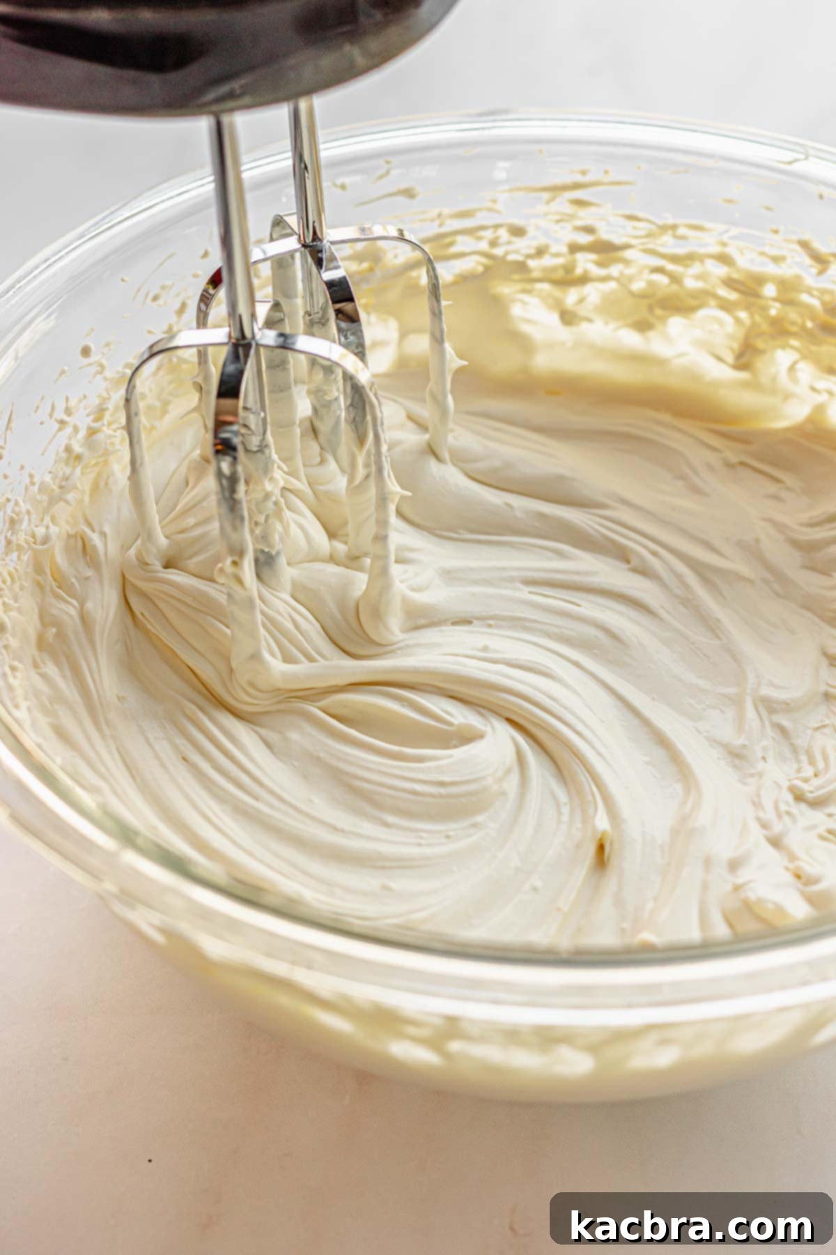 Beaters in a bowl beating fluffy mascarpone.