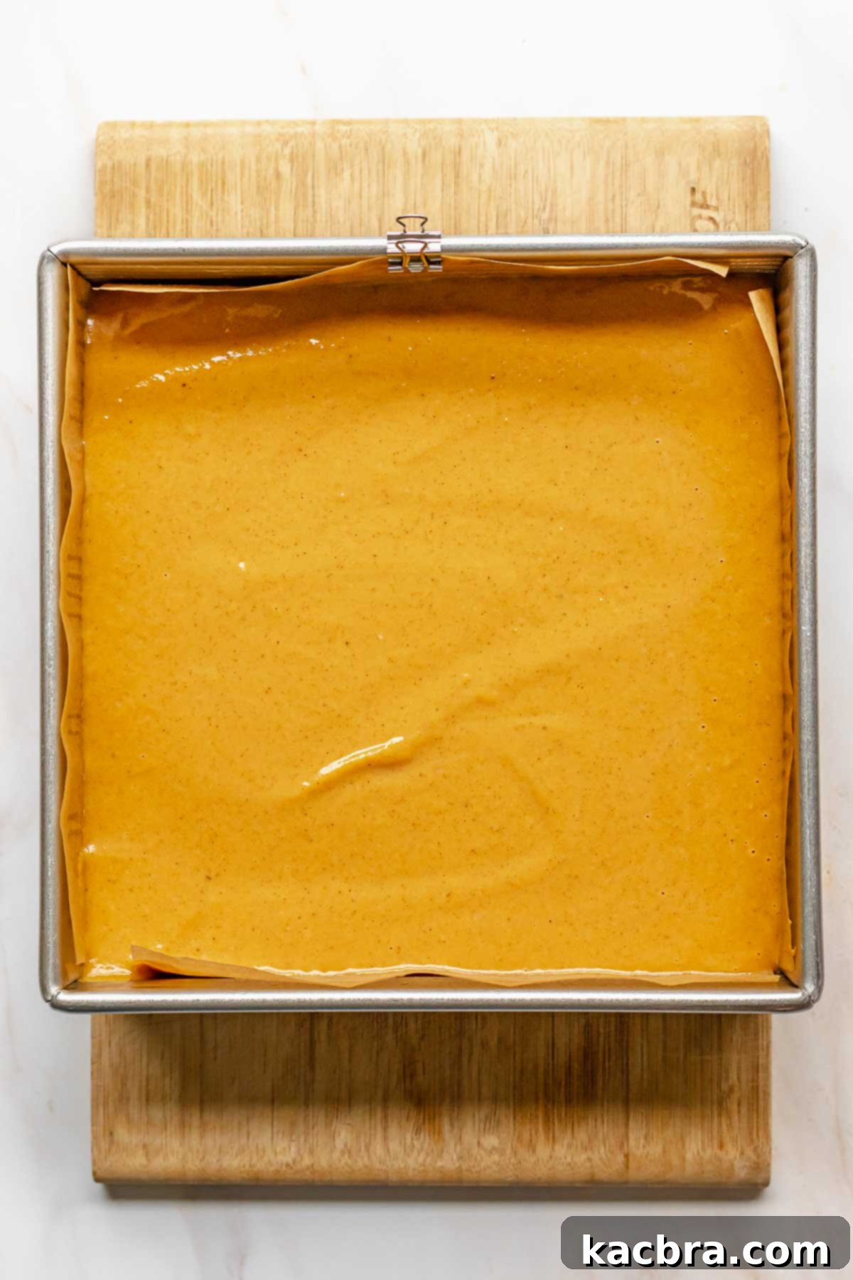 Unbaked sweet potato pie bars in a square pan, with the smooth filling poured over the crust.