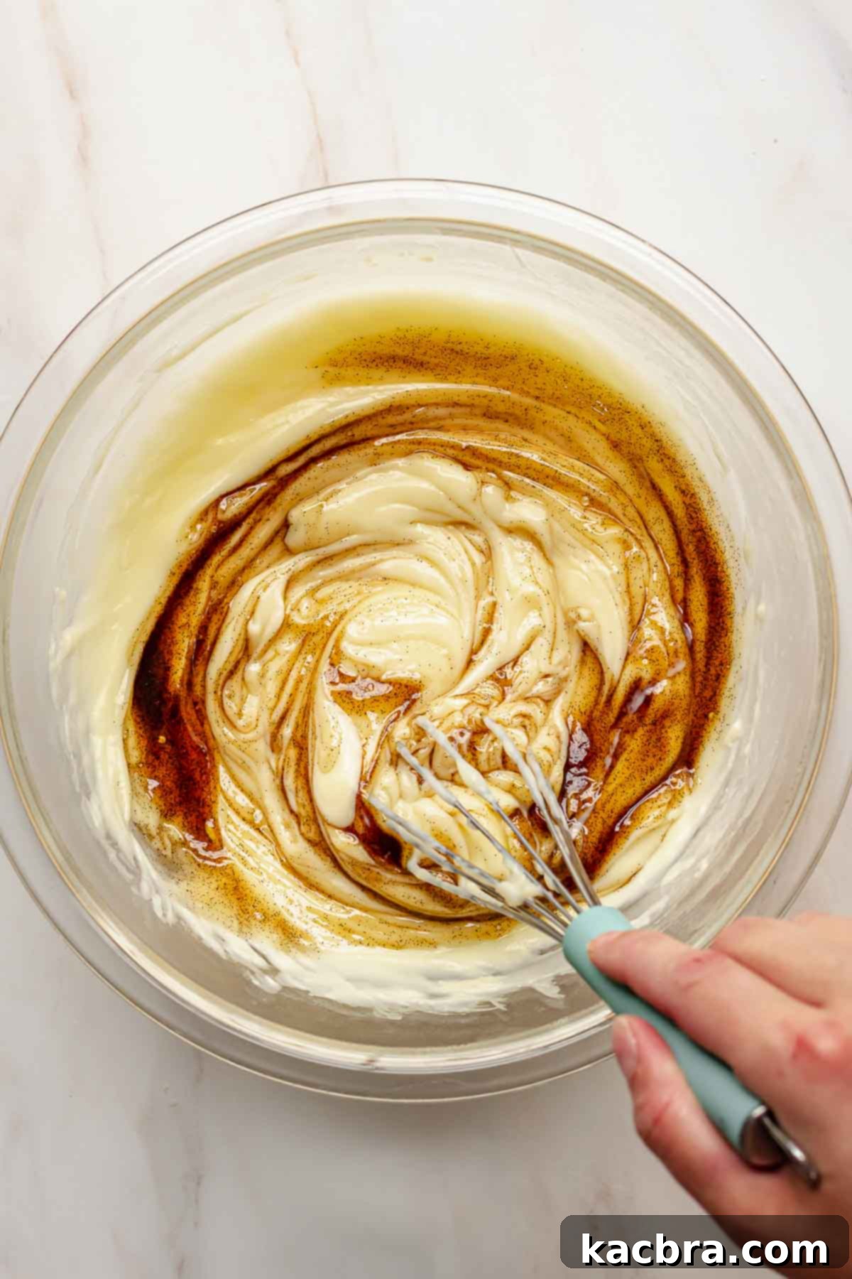 A hand whisking vanilla paste into the finished vanilla pudding.