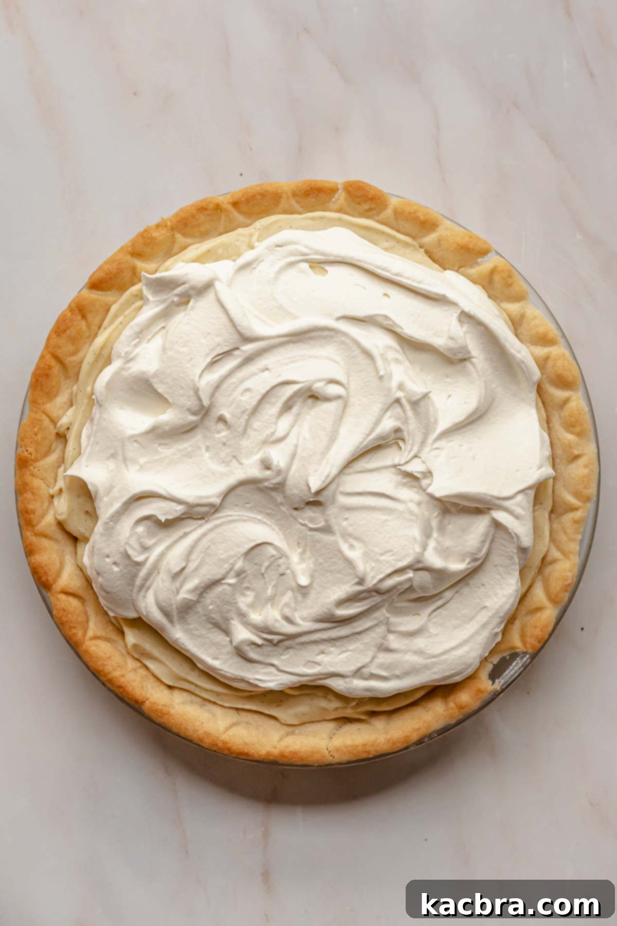 Freshly whipped cream artfully swirled on top of the vanilla pudding layer in the pie.