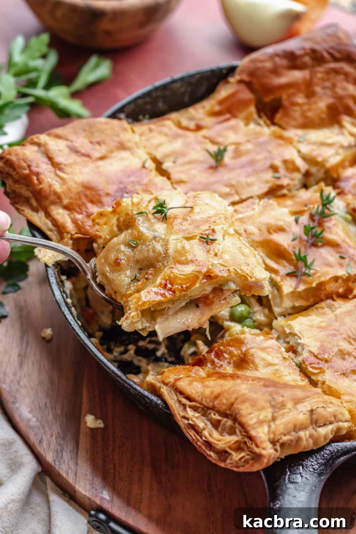 A close-up side view of a beautifully baked turkey pot pie in a cast iron skillet, highlighting the golden, perfectly risen puff pastry crust and the bubbling filling beneath.