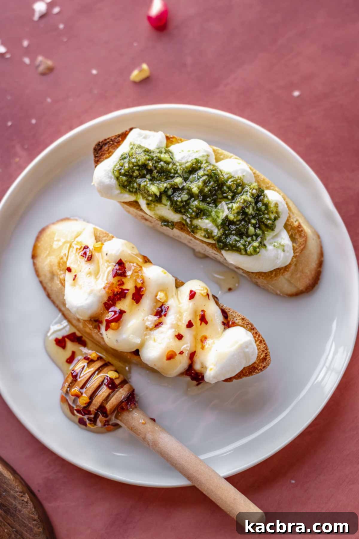 Fluffy Ricotta Crostini 3 Two crostinis on a plate, one topped with hot honey and one topped with pesto.