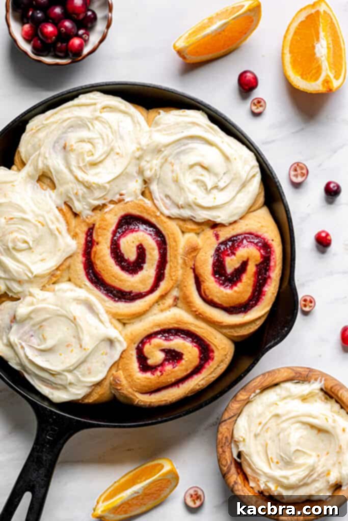Close-up of a frosted Cranberry Orange Roll, showcasing its soft texture and generous topping.