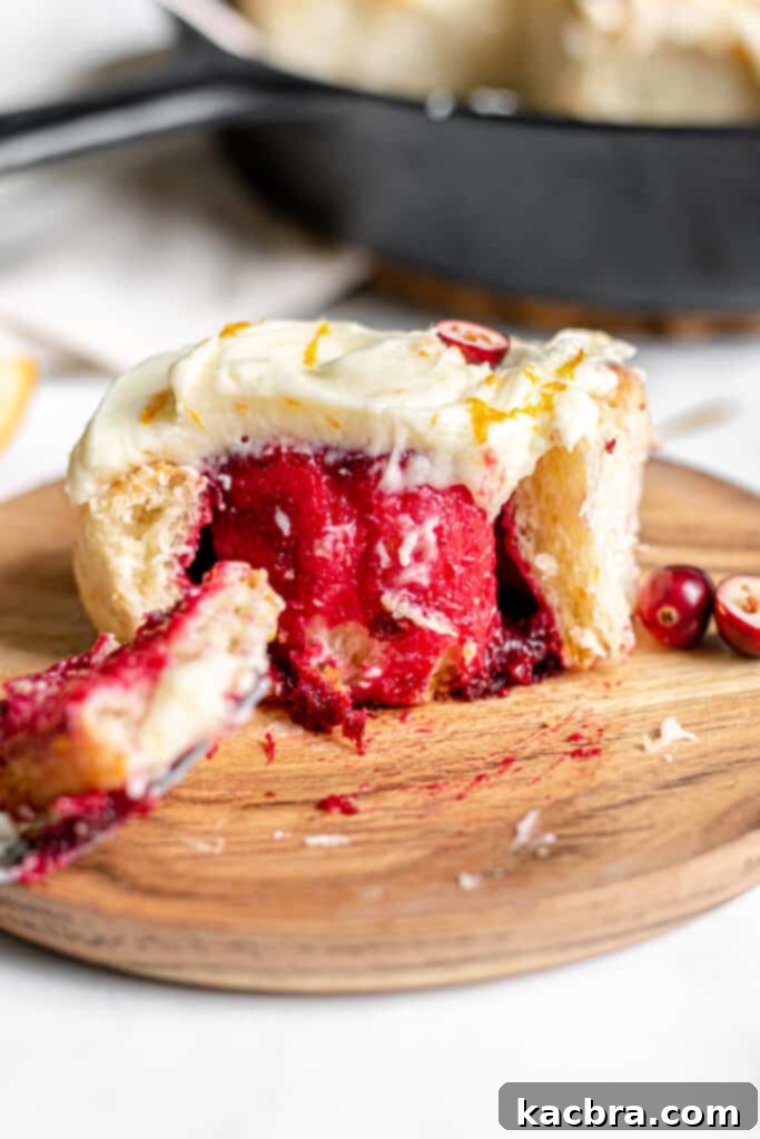 A top-down shot of finished Cranberry Orange Rolls on a wire rack, with some already frosted.