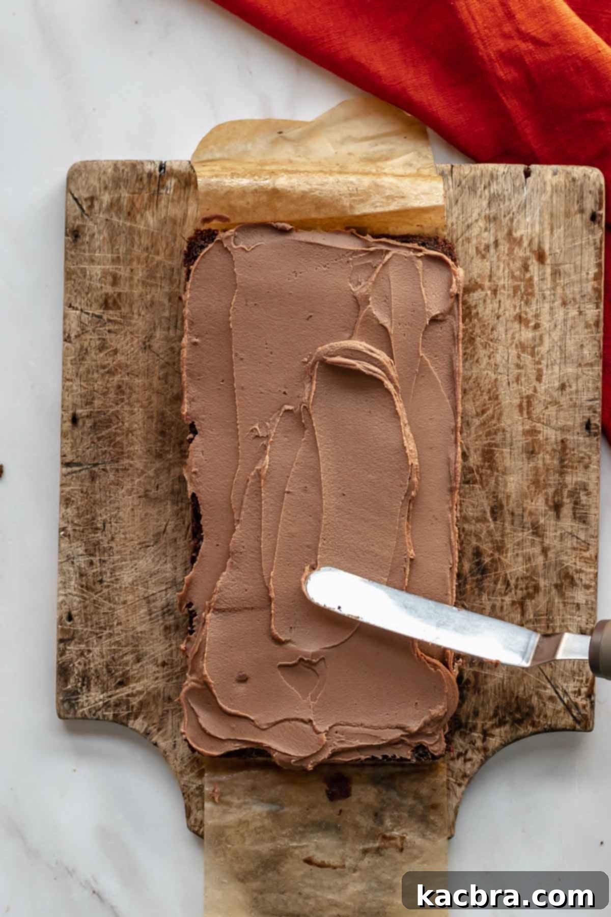 Decadent Chocolate Orange Bliss 12 A spatula spreads milk chocolate ganache onto a layer of cake, perfectly filling the space between the cake layers.