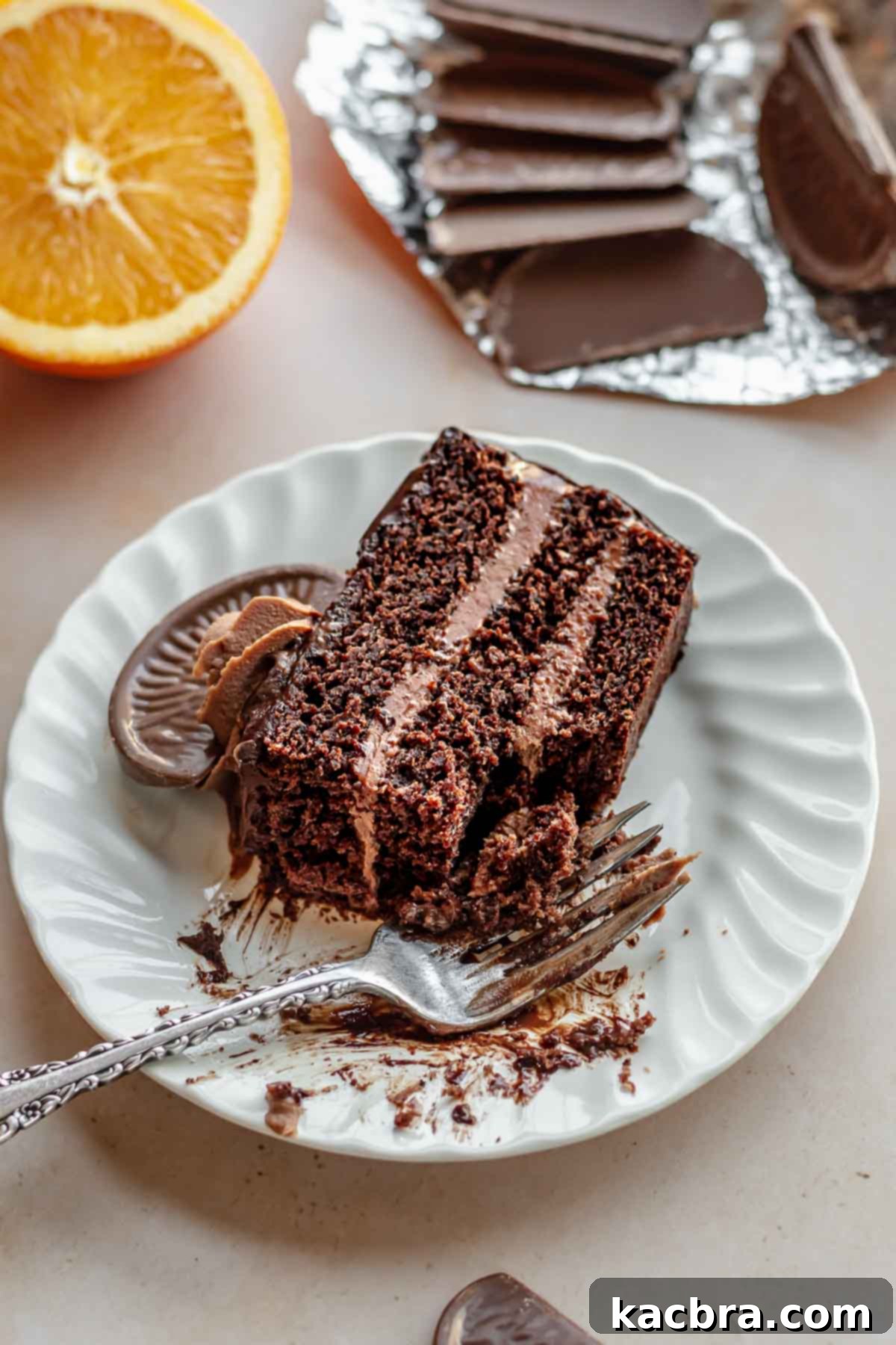 Decadent Chocolate Orange Bliss 17 A close-up of a delectable slice of Terry's Chocolate Orange cake on a white plate, with a fork poised and a small bite already taken, highlighting its irresistible layers and moist crumb.