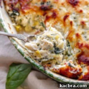 A spoonful of hot crab spinach artichoke dip, showing its rich texture.
