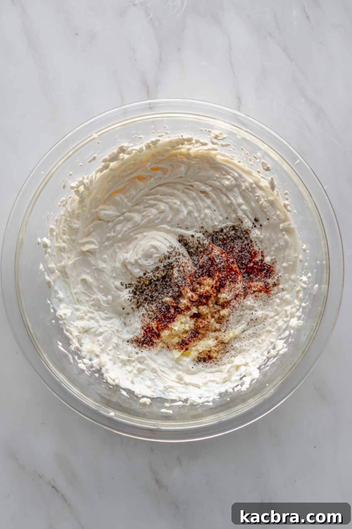 Minced garlic and cayenne pepper are added on top of the creamed wet ingredients in a bowl.