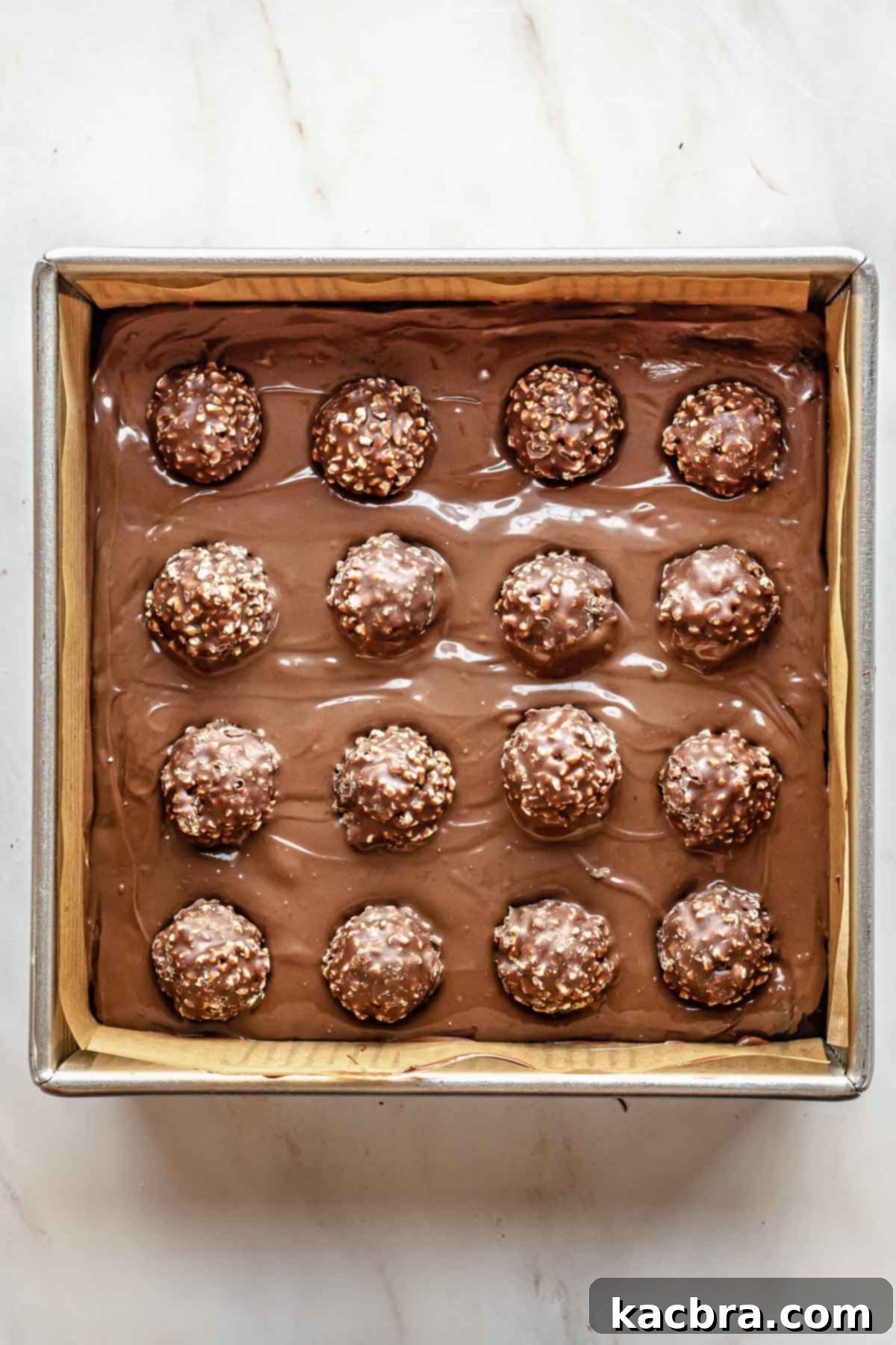 16 Ferrero rocher balls on top of the Nutella and brownie batter in a pan.