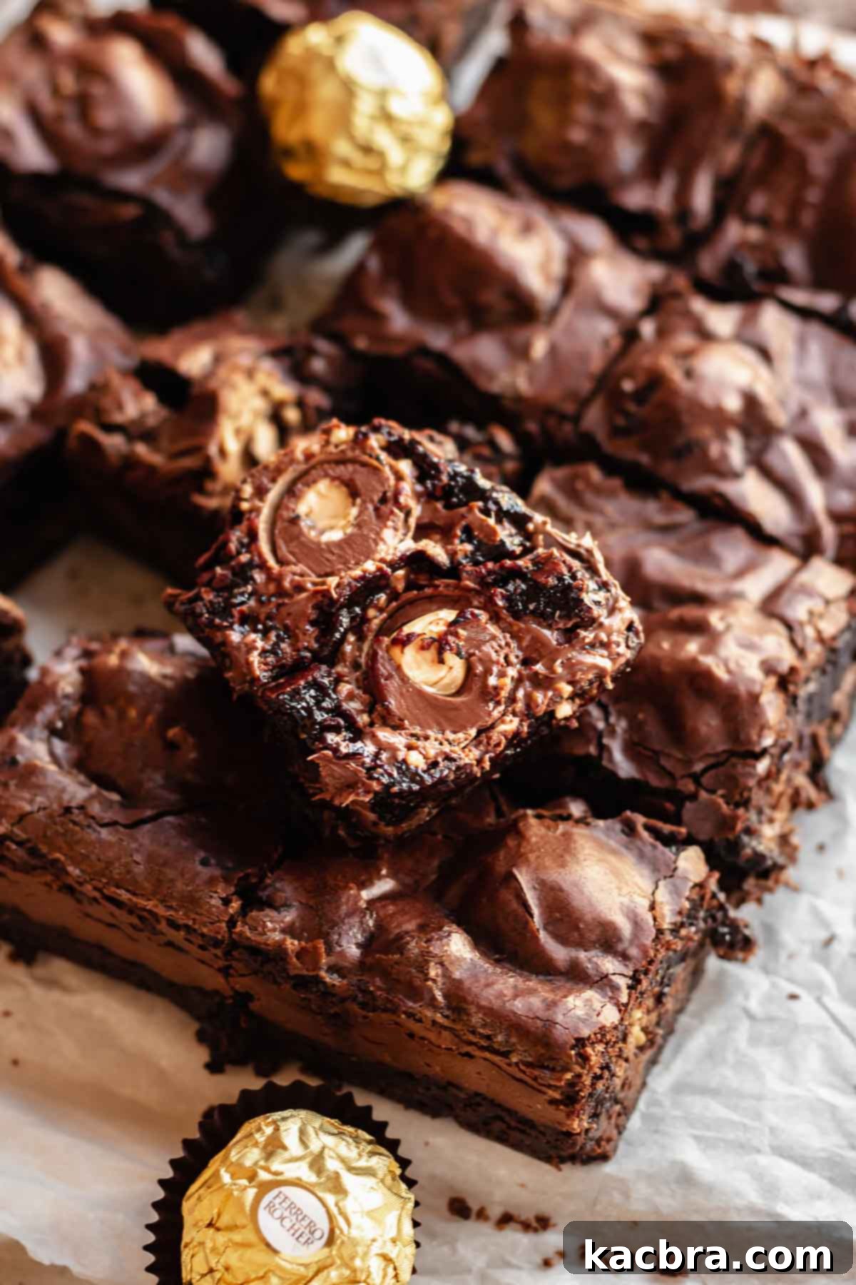 Broken open Ferrero rocher brownie laying on top of cut brownies.