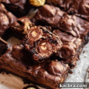 Broken open Ferrero rocher brownie laying on top of cut brownies.