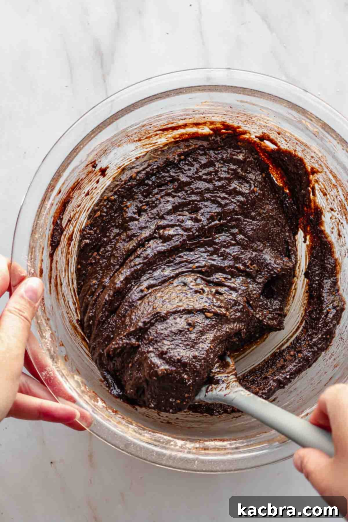 A spatula folds together brownie batter.