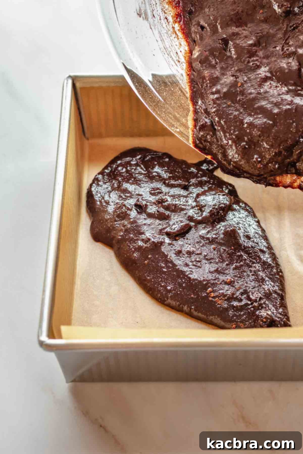 Brownie batter pouring into a prepared pan.