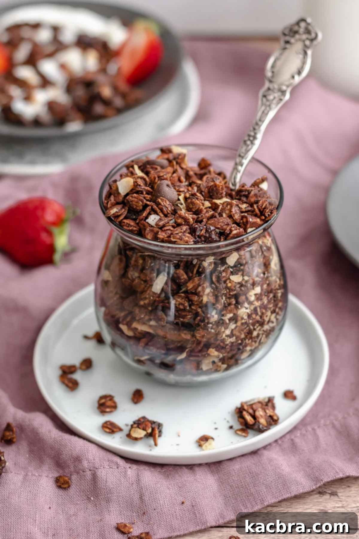 Chocolate granola in a cup with a spoon in it.