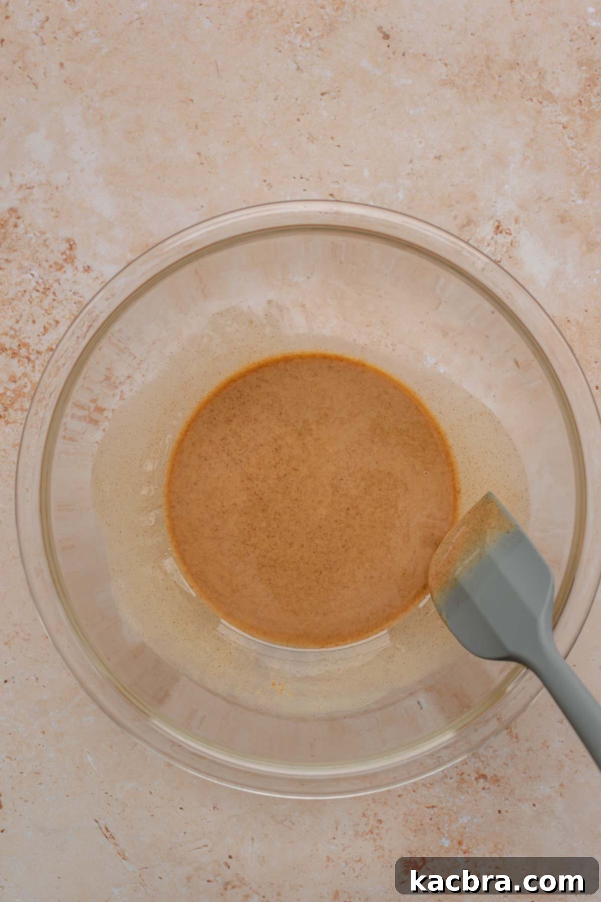 Melted coconut oil and almond butter being mixed in a bowl.