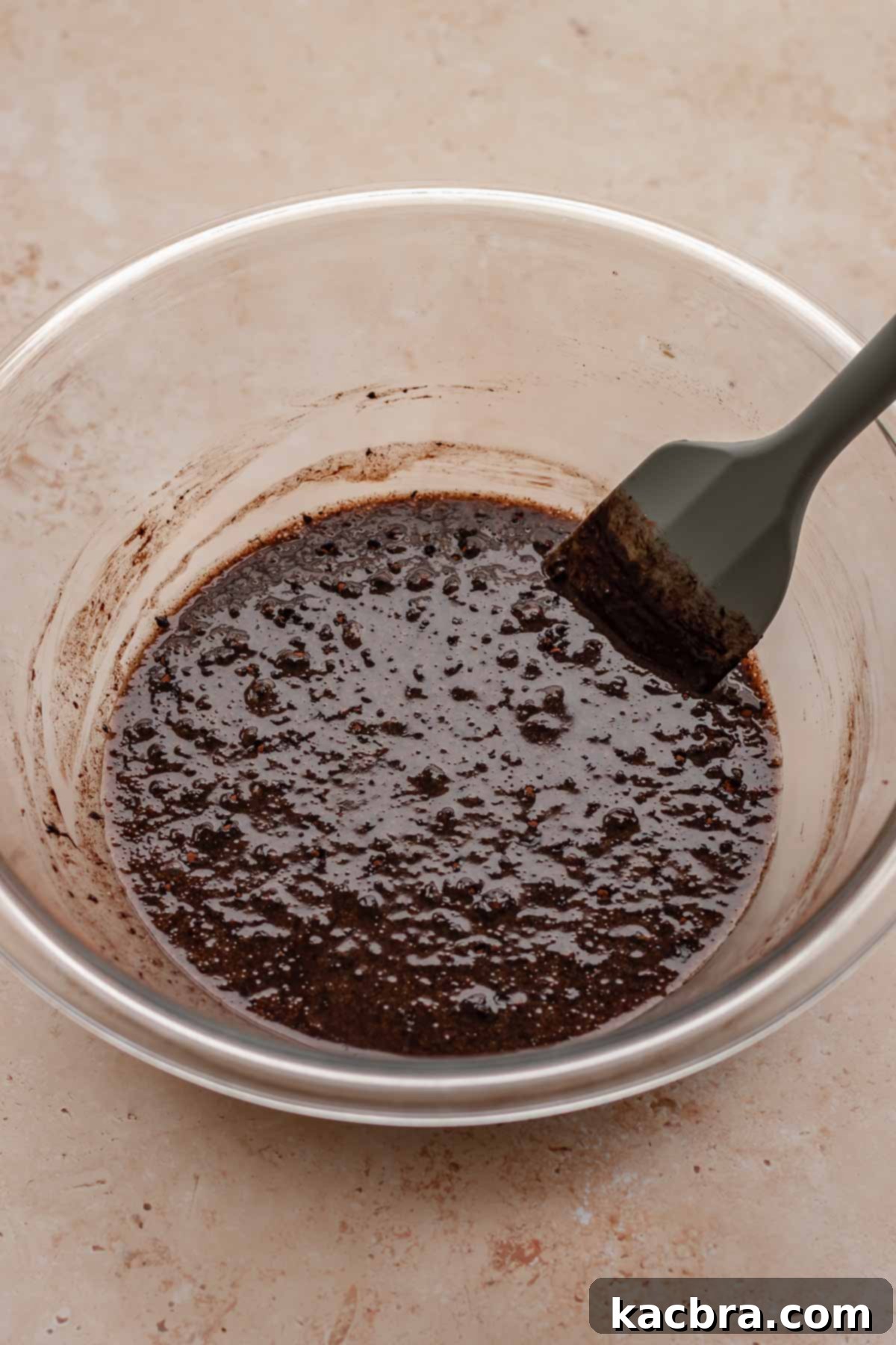 Chocolate mixture in a bowl with a spatula, ready for dry ingredients.