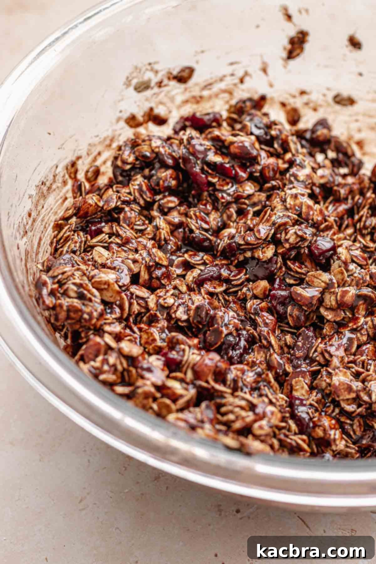 All granola ingredients mixed in a bowl, coated with chocolate.
