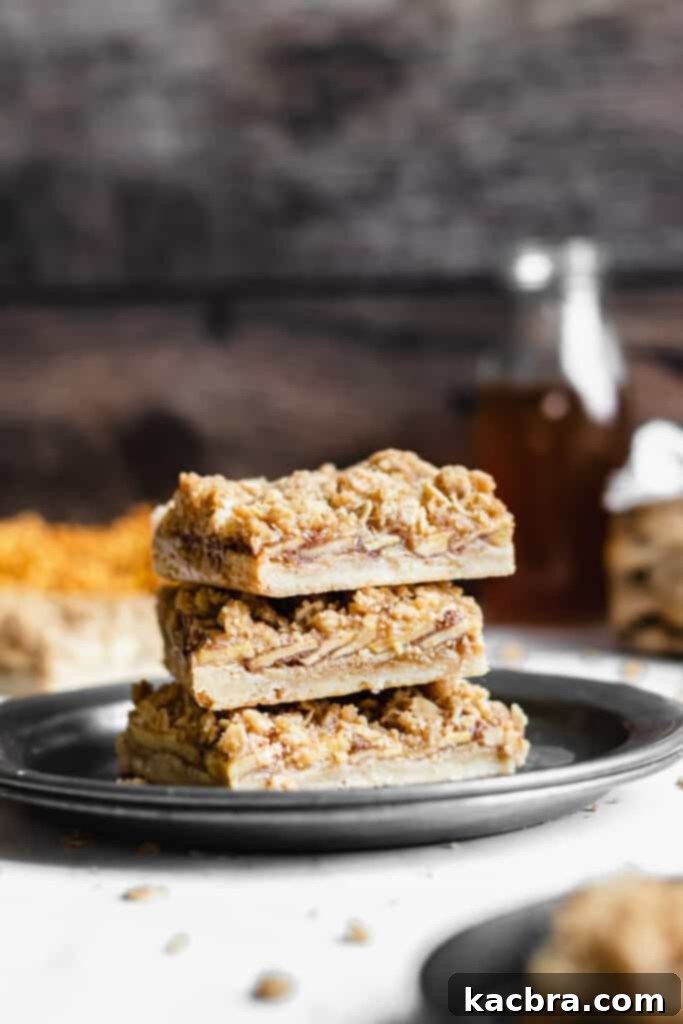 a stack of apple crisp bars on a place with apple cider in the background 