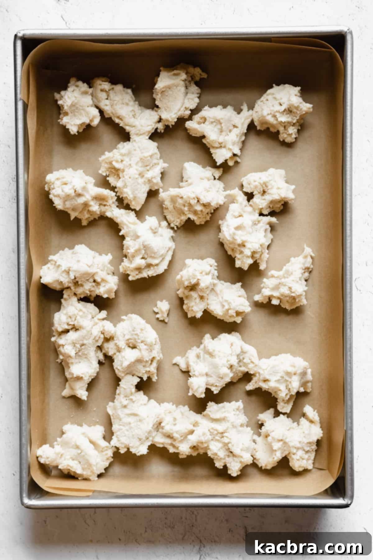 Chunks of shortbread scattered around a prepared pan.