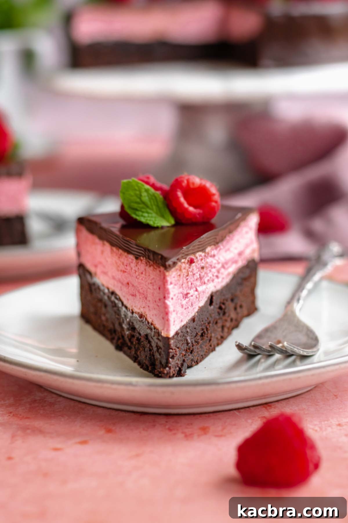 Piece of raspberry mousse cake on a plate, showcasing its beautiful layers.