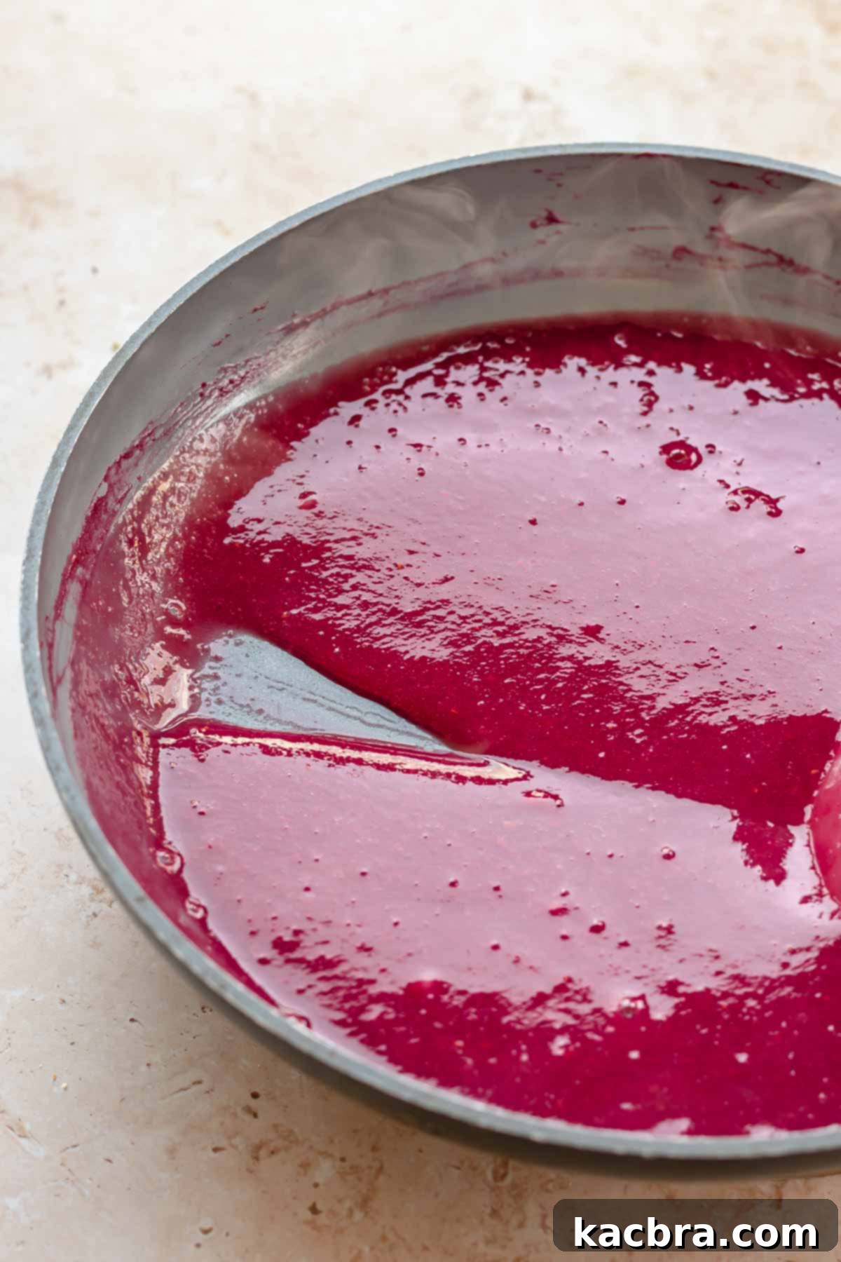 Raspberry puree gently simmering in a pan with sugar.
