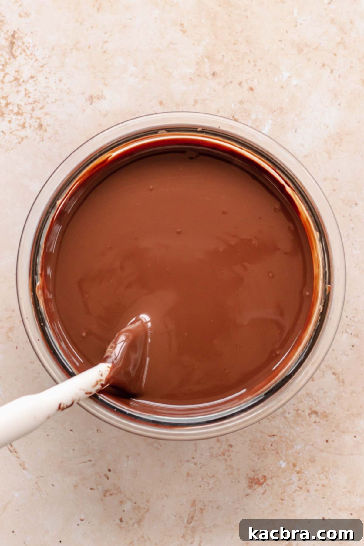 Melted chocolate ganache in a bowl, smooth and ready to pour.