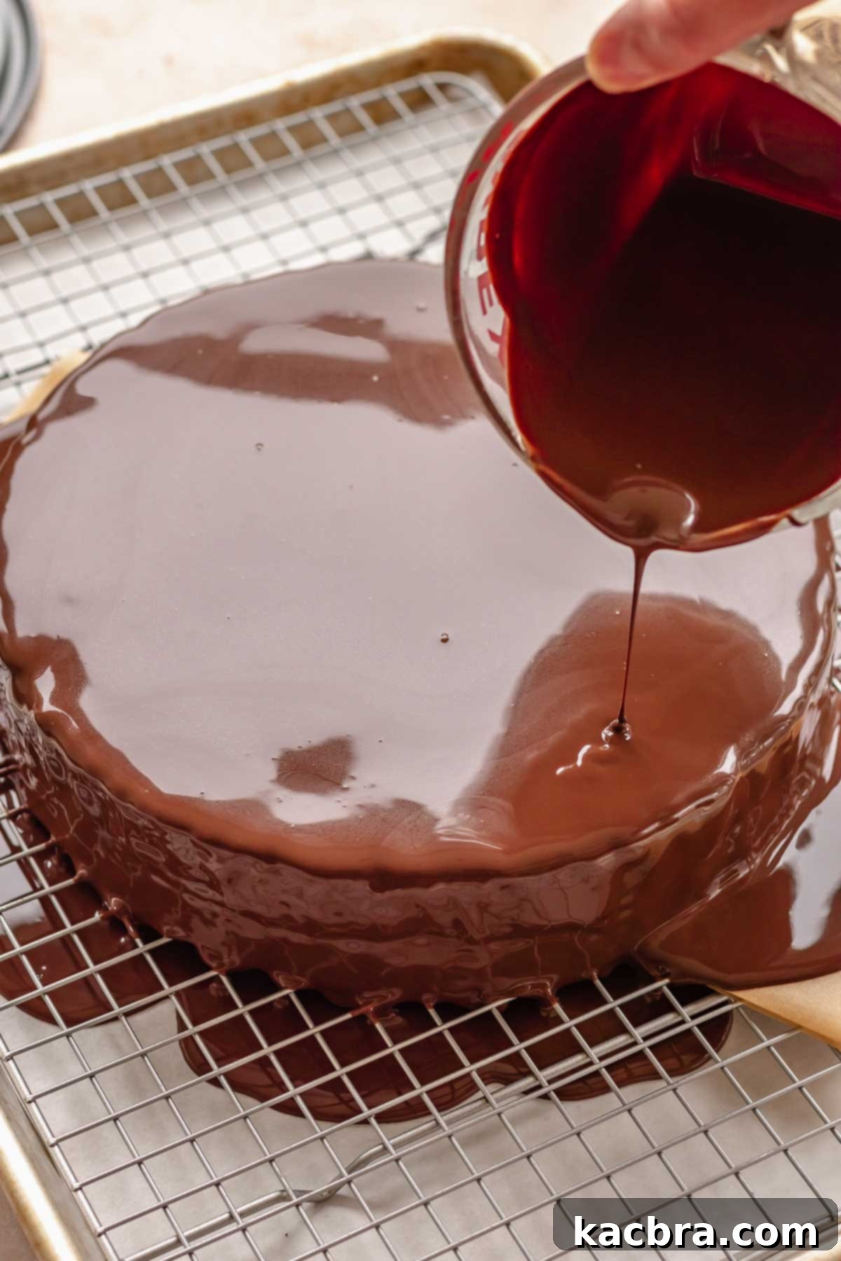 Chocolate ganache being carefully poured over the chilled cake.