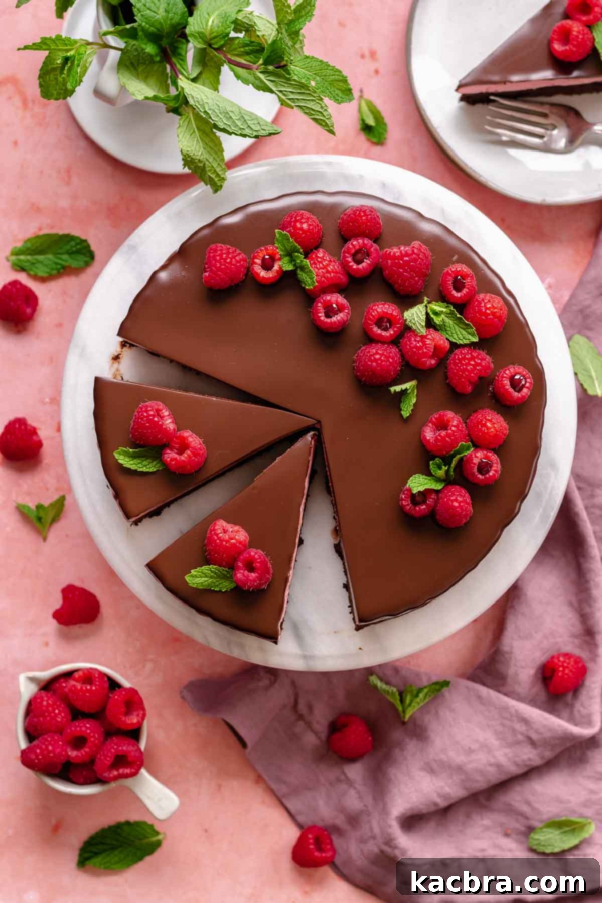 Chocolate raspberry mousse cake decorated on a platter with slices cut, showing its beauty.